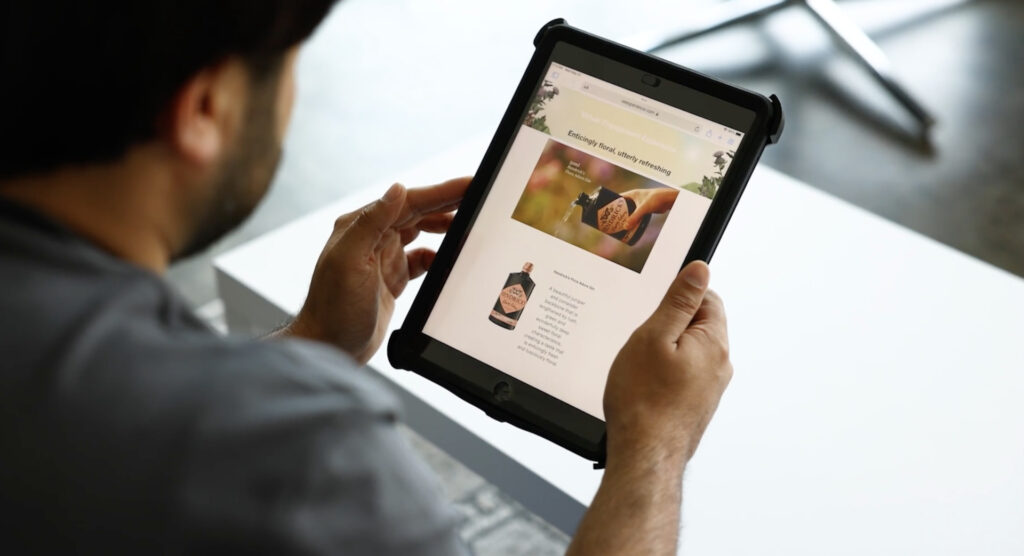 A man scrolling on an iPad looking at a Product Connections made landing page featuring Hendricks