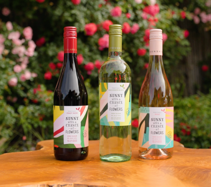 Sunny with a Chance of Flowers wine bottles in front of a rose bush